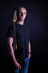 Young caucasian adult posing with electric guitar in the studio