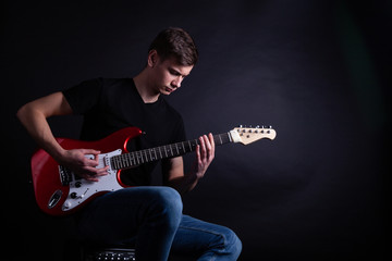 Obraz premium Young caucasian adult playing guitar in the studio