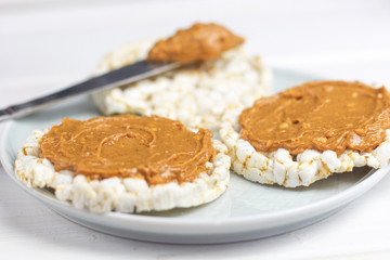crunchy natural peanut butter sandwich with rice cake bread and knife with peanut butter on plate. Proper nutrition diet vegetarian breakfast
