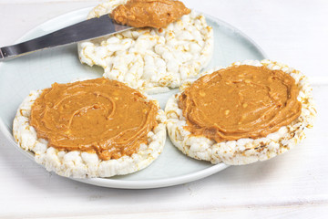 crunchy natural peanut butter sandwich with rice cake bread and knife with peanut butter on plate. Proper nutrition diet vegetarian breakfast