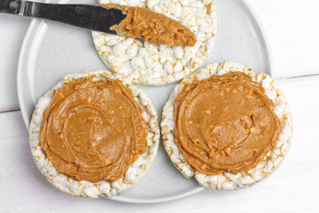 crunchy natural peanut butter sandwich with rice cake bread and knife with peanut butter on plate....