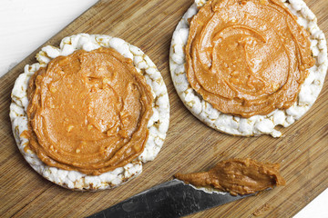crunchy natural peanut butter sandwich with rice cake bread and knife with peanut butter on plate. Proper nutrition diet vegetarian breakfast