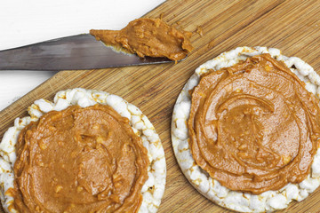 crunchy natural peanut butter sandwich with rice cake bread and knife with peanut butter on plate. Proper nutrition diet vegetarian breakfast