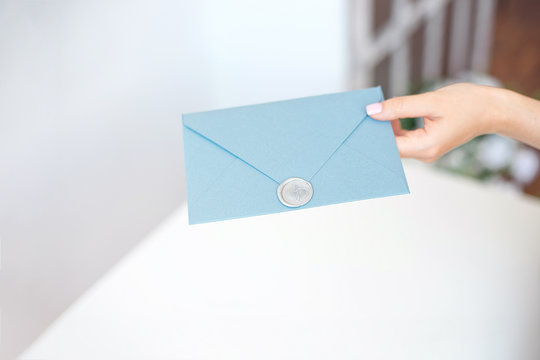 Close-up woman with slim body holding in hands the invitation card blue color square shape envelope card