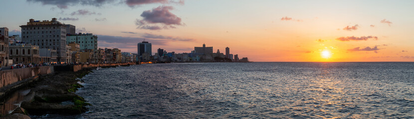 Beautiful Panoramic view of the Old Havana City, Capital of Cuba, by the ocean coast during a vibrant cloudy sunset.
