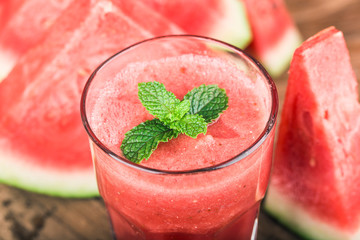 A glass of fresh watermelon juice on a wooden board background