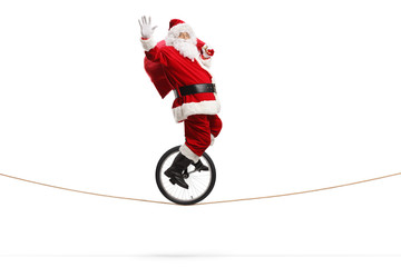 Santa claus riding a unicycle on a rope, waving and carrying a bag with presents © Ljupco Smokovski