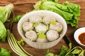 a bowl of beef ball soup on a wooden board background