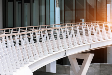 Obraz premium White pedestrian bridge with wooden handrails in the modern area of the city.