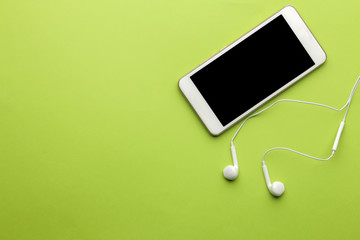 Smartphone. White phone and headphones on a bright green background. top view. space for text