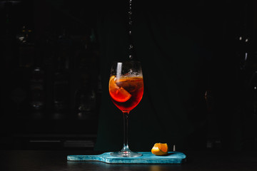 Bartender pours a sparkling wine with Aperol for Cocktails. Black background