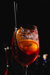 Red Wine glass with aperol spritz, italian alcoholic cocktail maked with aperol and sparkling wine, on dark background