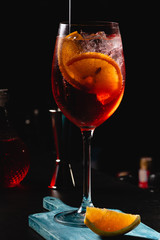 Red Wine glass with aperol spritz, italian alcoholic cocktail maked with aperol and sparkling wine, on dark background