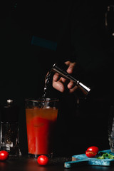 Bartender add vodka in Bloody Mary Caocktails, making a cocktail, maked with tomato Juice and vodka