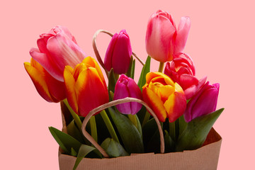 Fresh pink tulip flowers in paper bag isolated on white. Beautiful bouquet of tender colorful tulips in blank paper shopping bag. Greeting concept. Copy space, close up