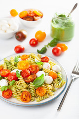 healthy fusilli pasta with pesto sauce, roasted tomatoes, mozzarella