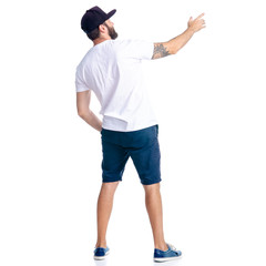 Man in shorts and cap standing looking showing pointing on white background isolation, back view