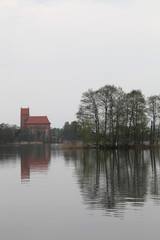 Fototapeta na wymiar The reflections of the trees and the castle off the lake water on a cloudy day.