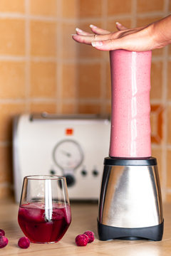 Woman hand blending fruit shake on the kitchen table with cherries