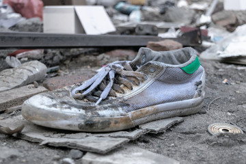 Old, dirty white sneaker, discarded in a landfill