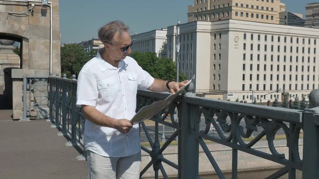 man looks at a paper map of the city and goes to look at the historical place