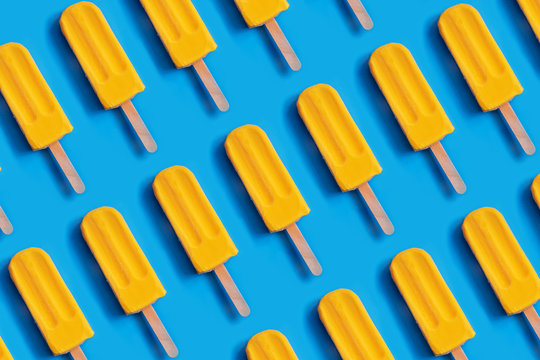 Pattern Made Of Bright Yellow Mango Ice Cream On Blue Pastel Background.