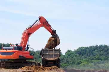 Excavator loading dumper truck on mining site 