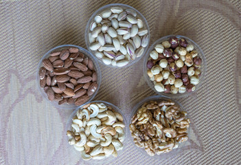 Fototapeta premium Healthy food. Nuts mix assortment on stone texture top view. Collection of different legumes for background image close up nuts, pistachios, almond, cashew nuts, peanut, walnut. image