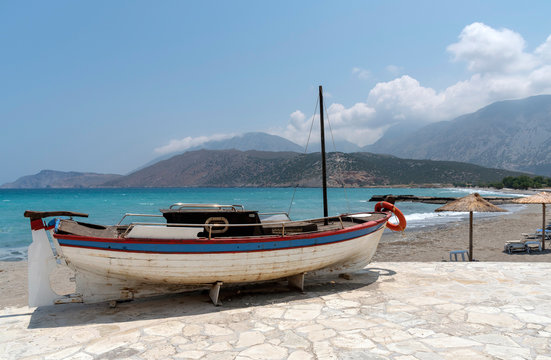 Crete, Greece. June 2019. A small boat painted red white blue with a background of the coast and mountains