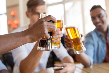 drinks, leisure and celebration concept - happy male friends drinking beer and clinking glasses at bar or pub