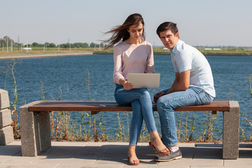 Man and woman using laptop outdoors. Image of young couple man and woman in casual clothes.
