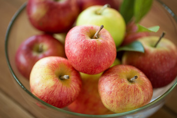 fruits, food and harvest concept - ripe apples in glass bowl on wooden table