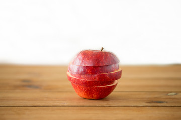fruits, food and harvest concept - sliced red apple on wooden table