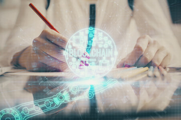 Cryptocurrency hologram over woman's hands writing background. Concept of blockchain. Double...