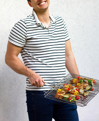 Handsome male preparing barbecue outdoor for BBQ friends party in garden and smiling, enjoing cooking at home. 