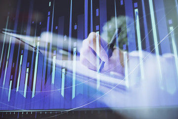 Financial forex graph displayed on hands taking notes background. Concept of research. Multi exposure