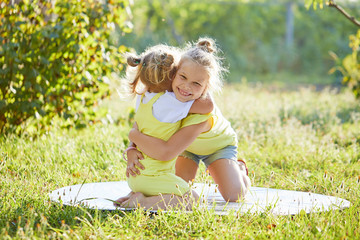 Fototapeta premium Portrait of two cute little girls smiling and playing at the garden. Sisters having fun and hugs