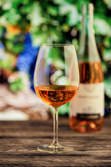 Glass of rose wine with blurred vineyard on background