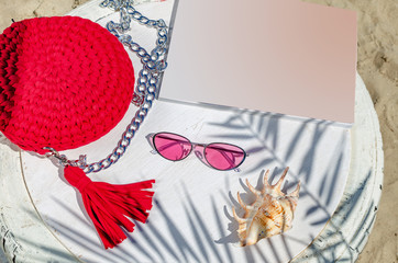 Small red women's handbag, pink sunglasses, magazine, cockleshell on a white background. Summer...