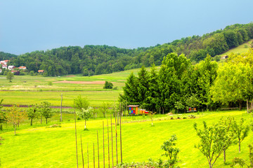 Fototapeta na wymiar Beautiful summer farmland Slovenian landscape with colorfull and vibrant bee hives. Green meadow in Skofljica, Slovenia.