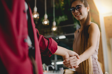 Two women businessmen join hands to agree to do business together.