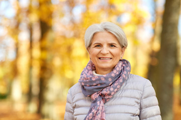 old age, retirement and season concept - portrait of happy senior woman at autumn park