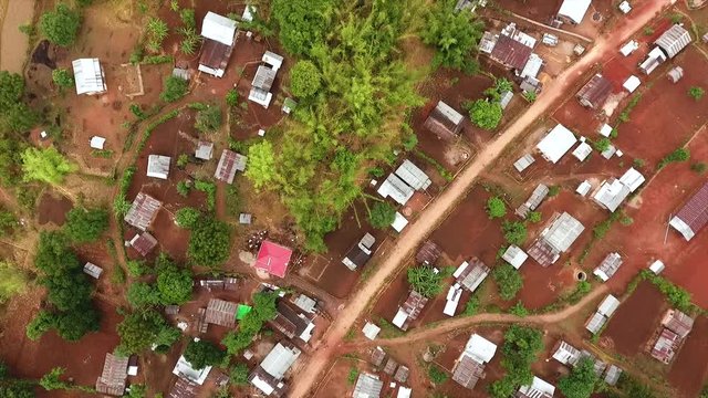 High-angle aerial pull back dolly shot of scattered farm houses near a countryside dirt road, Kalaw, Shan State, Myanmar