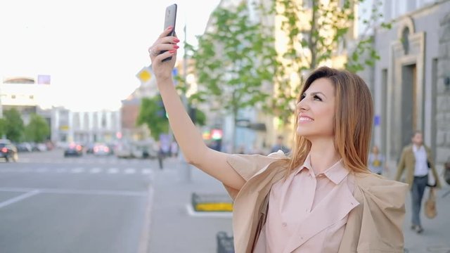 Taking selfie. Woman photographs herself in the city using mobile phone