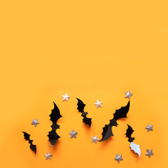 Halloween flat lay composition of black paper bats fly up and gold stars