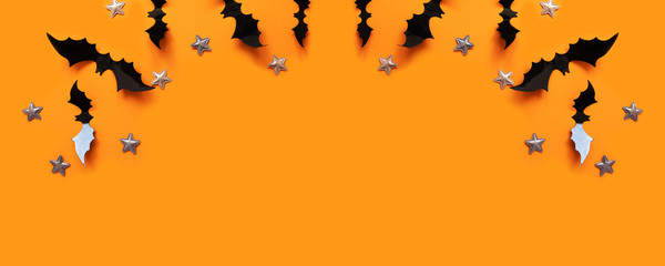 Halloween flat lay composition of black paper bats fly up and gold stars