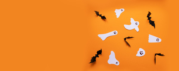 Halloween flat lay composition of orange pumpkin, black bats, white paper casts