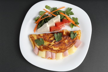 Dinner with omelette salami, salad pepper, cheese, tomato on black background.