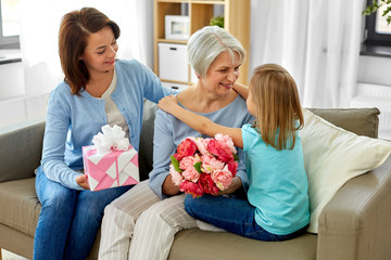 family, generation and birthday - happy mother with gift box and daughter hugging grandmother at home