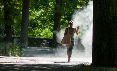 Portrait of woman walking in urban park in sprayer on back view